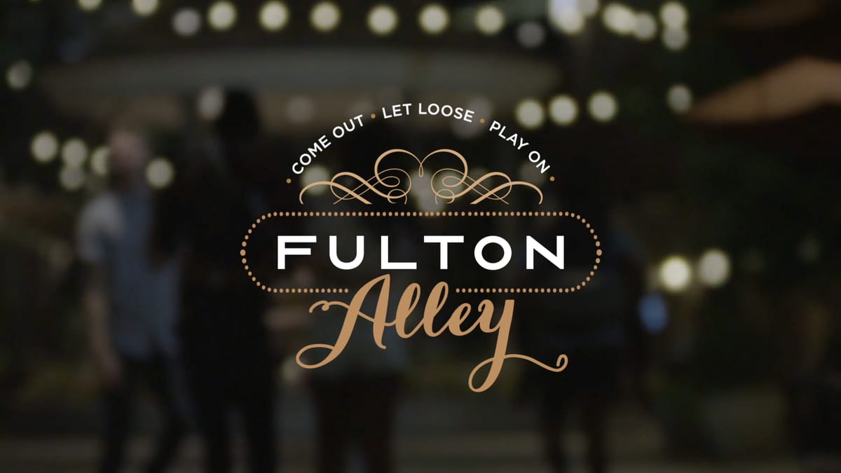 Fulton Alley logo over a blurred crowd under string lights